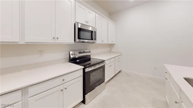 a kitchen with a sink a stove a refrigerator and white cabinets
