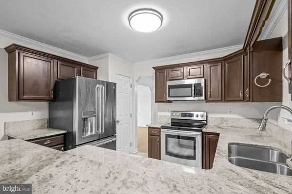 a kitchen with granite countertop a refrigerator and a sink