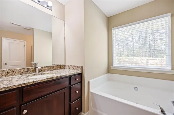 a bathroom with a granite countertop sink and a bathtub