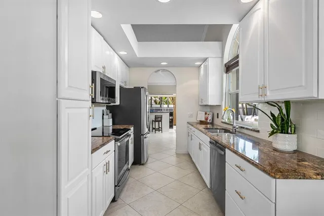 a kitchen with stainless steel appliances granite countertop a refrigerator a stove and a sink