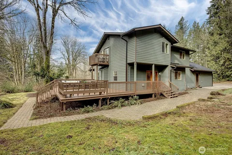 a backyard of a house with wooden deck patio and outdoor seating