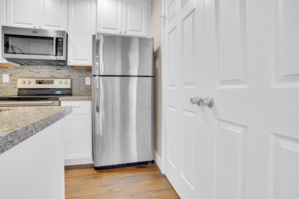 449 Harris Street, Unit I102 Coppell, TX 75019 - Photo 10 of 33 a kitchen with granite countertop a refrigerator a stove a microwave and cabinets