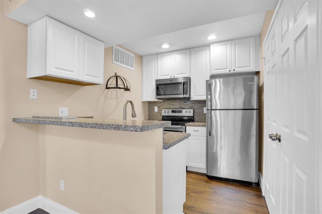 449 Harris Street, Unit I102 Coppell, TX 75019 - Photo 12 of 33 a kitchen with a refrigerator a stove top oven a sink and dishwasher with wooden floor