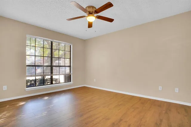 an empty room with wooden floor fan and windows