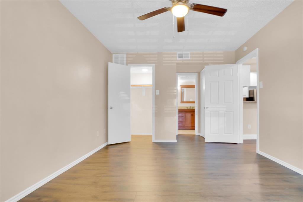 449 Harris Street, Unit I102 Coppell, TX 75019 - Photo 7 of 33 an empty room with wooden floor chandelier fan and windows