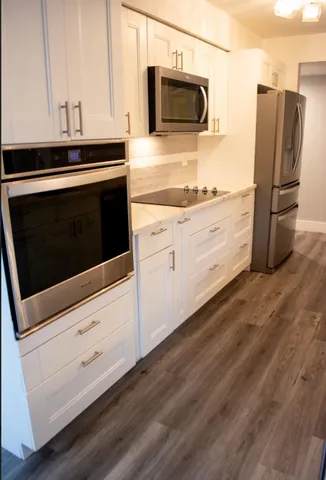 a kitchen with granite countertop cabinets stainless steel appliances and wooden floor