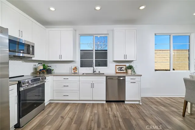 a kitchen with stainless steel appliances granite countertop a refrigerator stove a sink and dishwasher with wooden floor