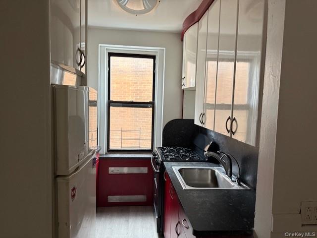118-14 83rd Avenue, Unit 3G Queens, NY 11415 - Photo 4 of 12 Kitchen with stainless steel gas range oven, refrigerator, dark countertops, white cabinets, and light wood-style flooring