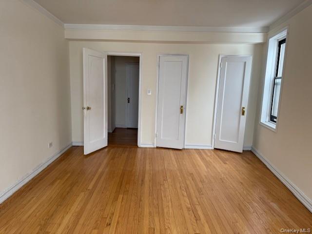 118-14 83rd Avenue, Unit 3G Queens, NY 11415 - Photo 7 of 12 Unfurnished bedroom featuring two closets, light wood-style flooring, and crown molding
