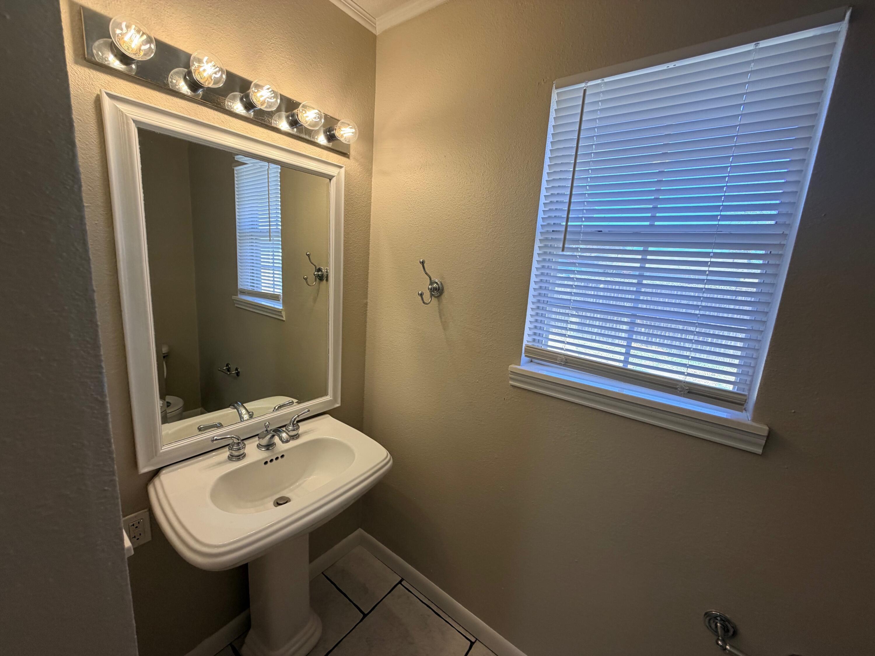 4310 42nd Street Lubbock, TX 79413 - Photo 12 of 25 a bathroom with a sink a mirror and a window