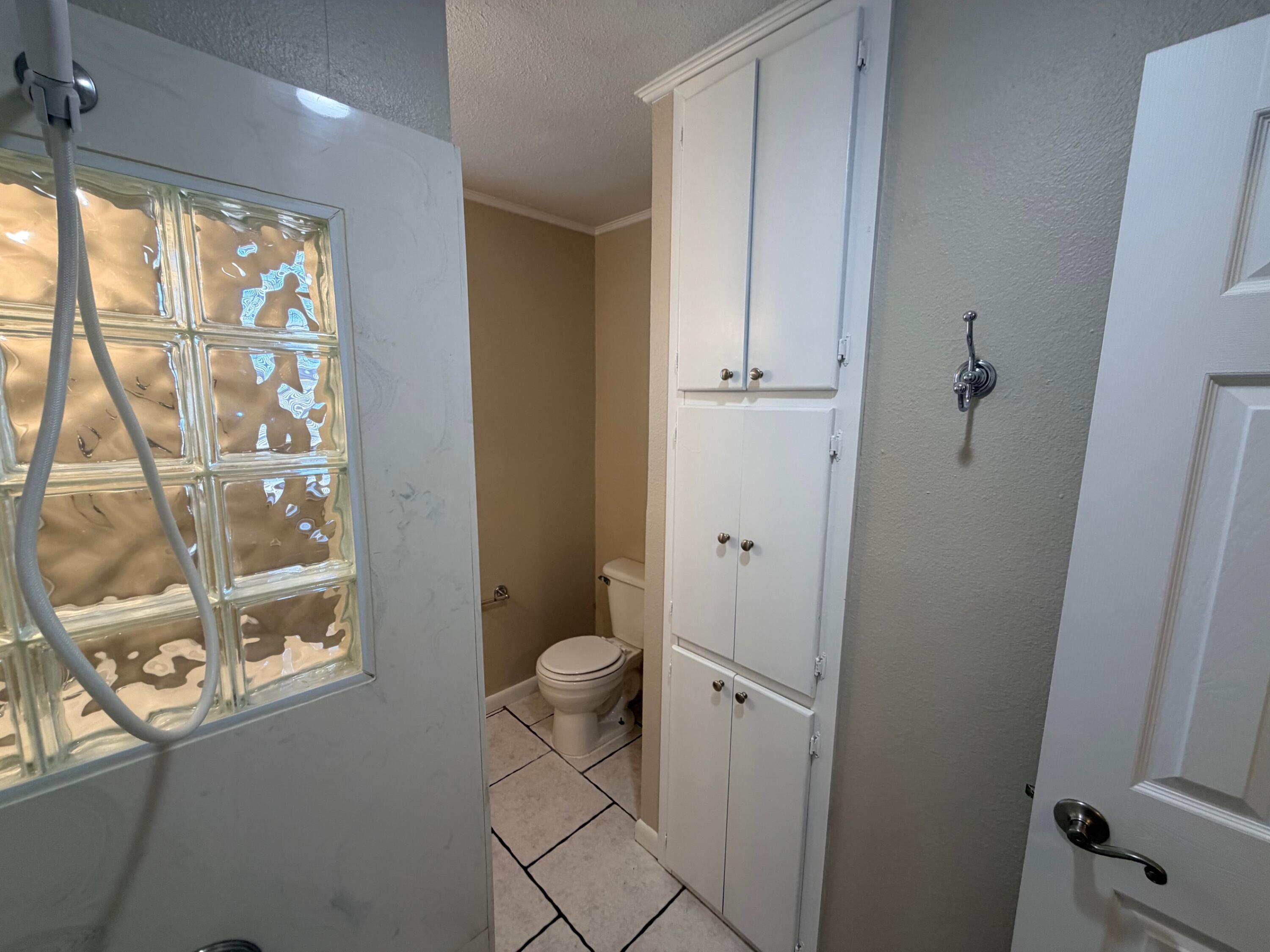 4310 42nd Street Lubbock, TX 79413 - Photo 14 of 25 a bathroom with a granite countertop sink a toilet a window and a shower