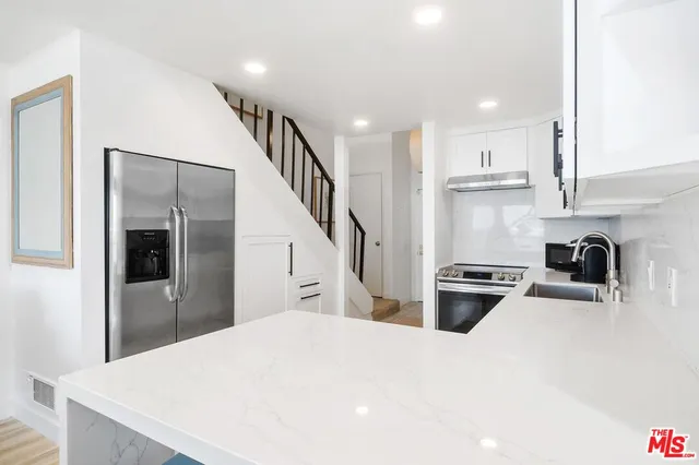 a kitchen with stainless steel appliances a stove a refrigerator a sink and a refrigerator