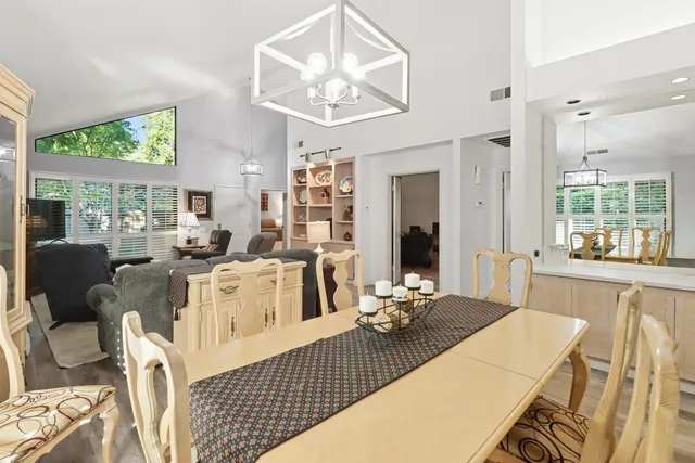 a living room with furniture a large window and dining table