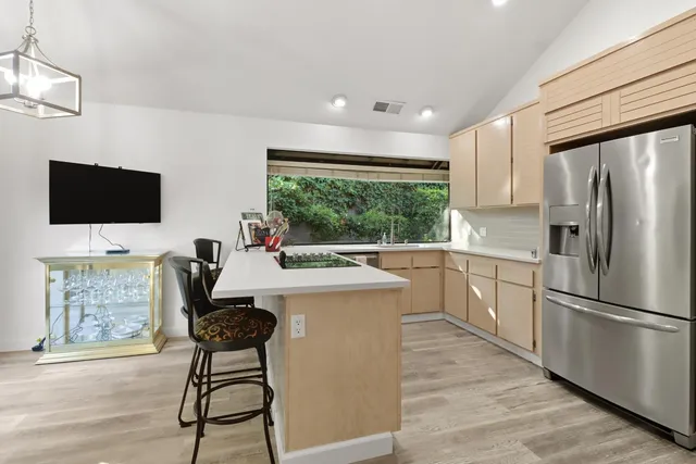 a kitchen with a table chairs refrigerator and a window