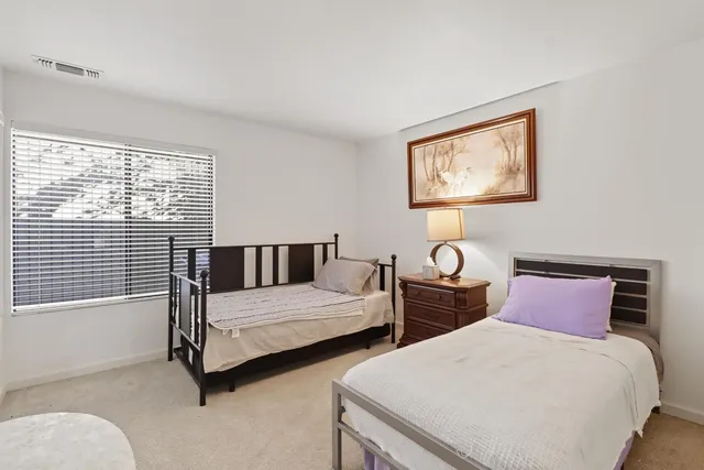 a bedroom with two beds and a table with exposed radiator
