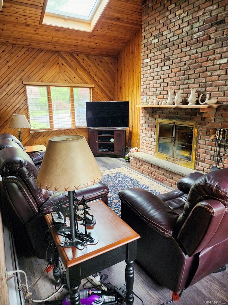 46 Cortlandt Road Mahopac, NY 10541 - Photo 7 of 32 Living area featuring a floor-to-ceiling brick fireplace with a wood mantel, wood-finish flooring, and a prominent skylight