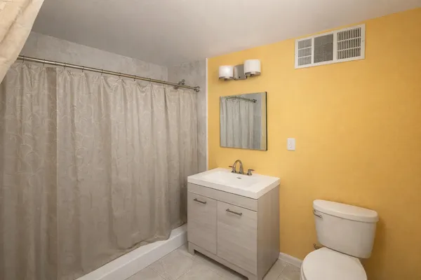 a bathroom with a toilet sink vanity and mirror