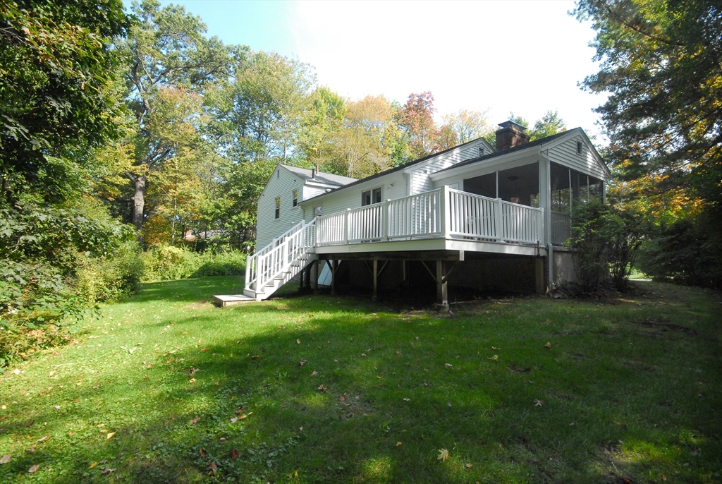 13 Beverly Road Acton, MA 01720 - Photo 23 of 23 a house that is sitting in the grass with large trees and plants