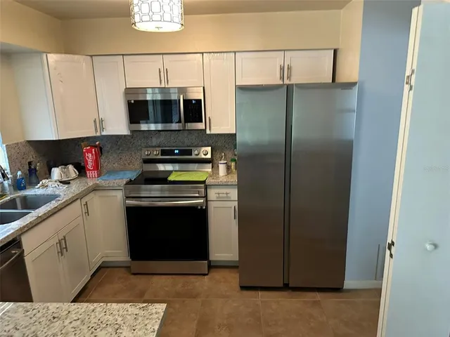 a kitchen with stainless steel appliances granite countertop a refrigerator and a stove