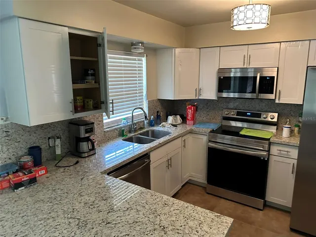 a kitchen with stainless steel appliances granite countertop a sink dishwasher stove and microwave with wooden floor