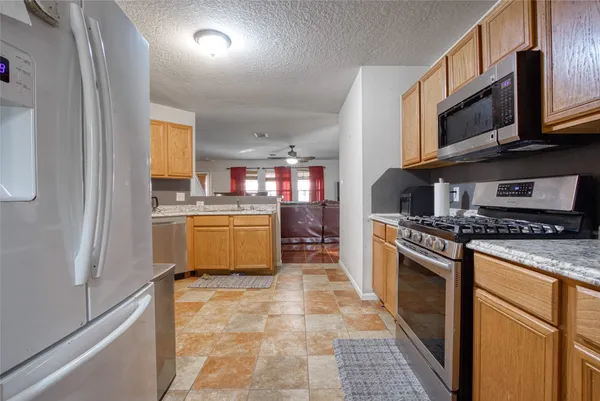 a kitchen with stainless steel appliances granite countertop a stove top oven a sink a counter space and cabinets