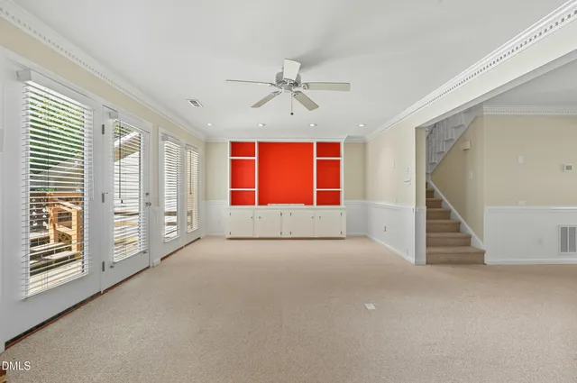 an empty room with windows and chandelier fan