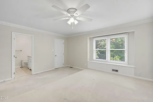 an empty room with chandelier fan and windows