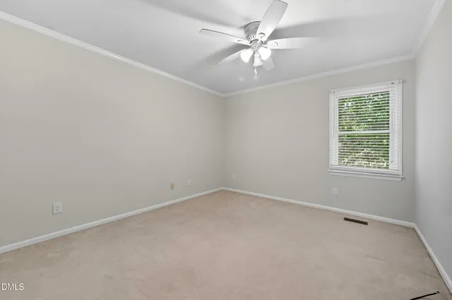 an empty room with a chandelier fan and windows