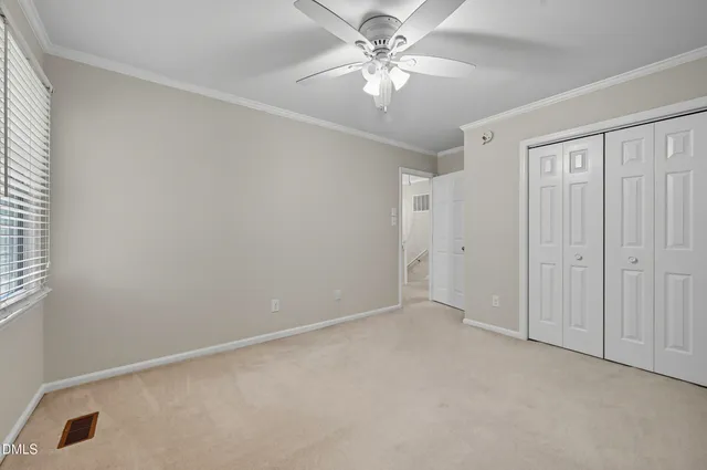 an empty room with a chandelier fan and windows