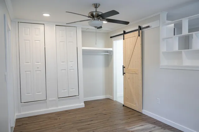 a view of empty room with wooden floor and fan