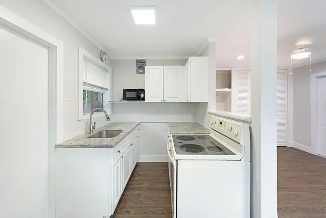 a kitchen with granite countertop a stove sink and cabinets