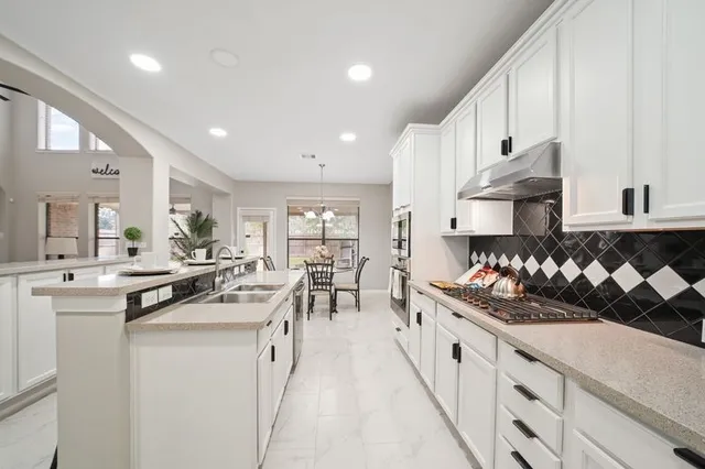 a kitchen with stainless steel appliances kitchen island granite countertop a sink a stove and cabinets