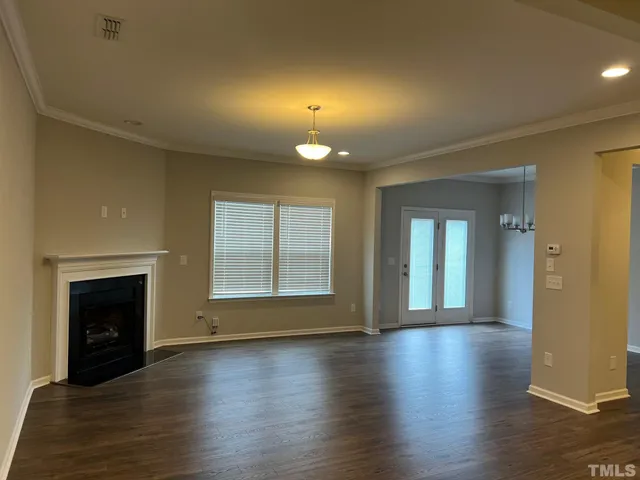 an empty room with wooden floor fireplace and windows