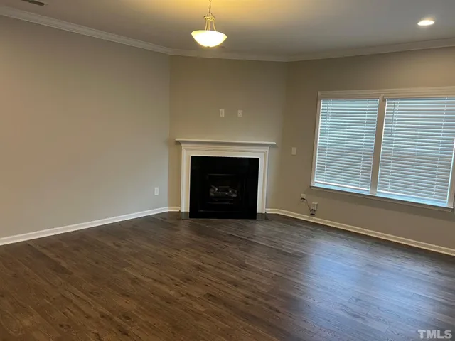 an empty room with wooden floor fireplace and windows