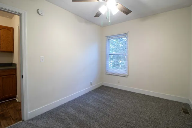 an empty room with windows and fan