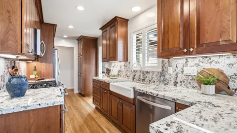 a kitchen with stainless steel appliances kitchen island granite countertop a sink a stove cabinets counter space and a window