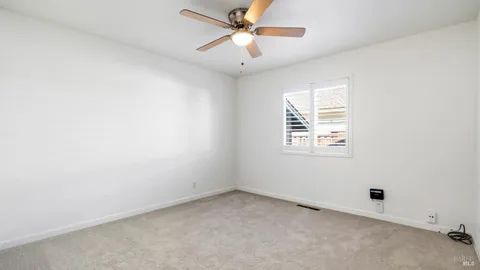 an empty room with a window and a ceiling fan