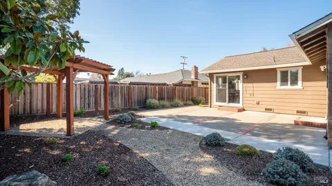 a backyard of a house with a tree and wooden fence