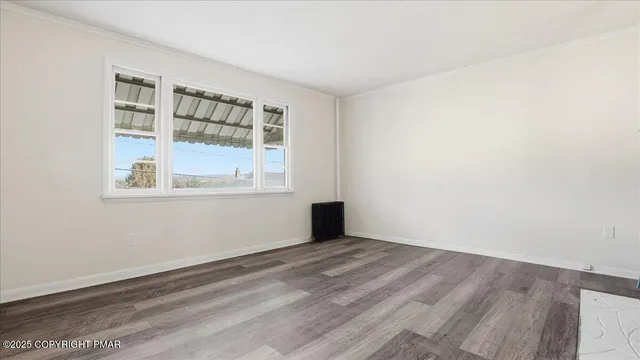 a view of an empty room with wooden floor fireplace and a window