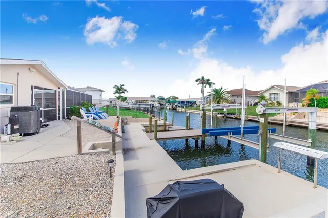 a kitchen with stainless steel appliances granite countertop a stove a sink a refrigerator and white cabinets with wooden floor