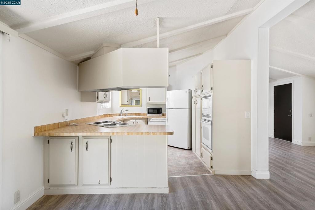 1201 Monument Boulevard Concord, CA 94520 - Photo 8 of 23 a kitchen with a stove a refrigerator and a wooden floor