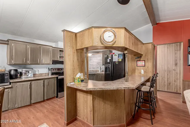 a kitchen with stainless steel appliances kitchen island granite countertop a stove a sink and a dining table with wooden cabinet