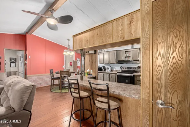 a kitchen with stainless steel appliances kitchen island granite countertop a table chairs stove and cabinets