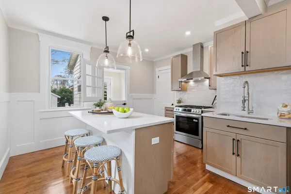 a kitchen with stainless steel appliances kitchen island granite countertop a stove a sink a dining table and chairs with wooden floor