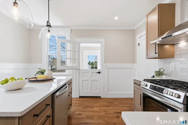 a kitchen with stainless steel appliances a stove a sink cabinets and wooden floor