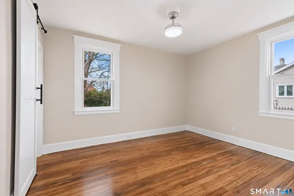 a view of empty room with wooden floor and fan