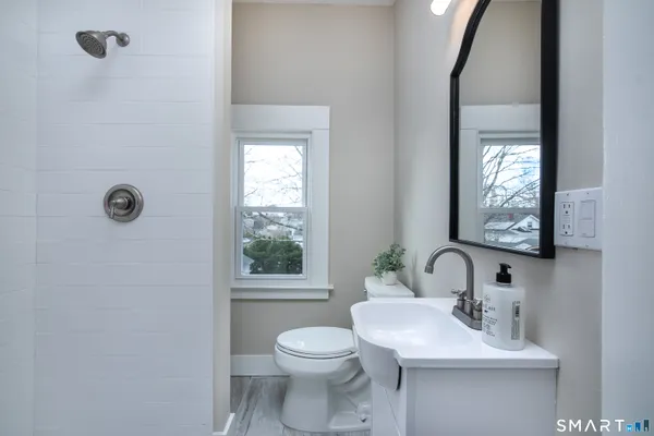 a bathroom with a toilet a sink a mirror and a window