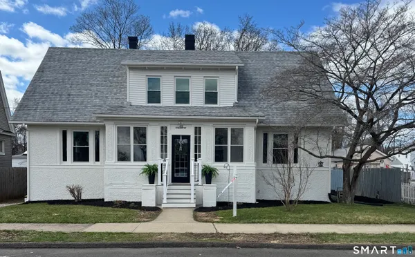 a view of a white house with large windows and a tree