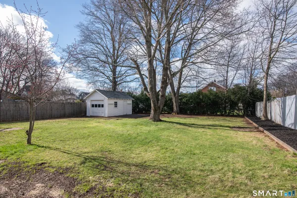 a view of backyard with wooden fence and large trees