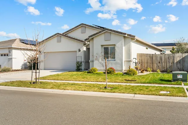 a view of a white house with a big yard and large trees